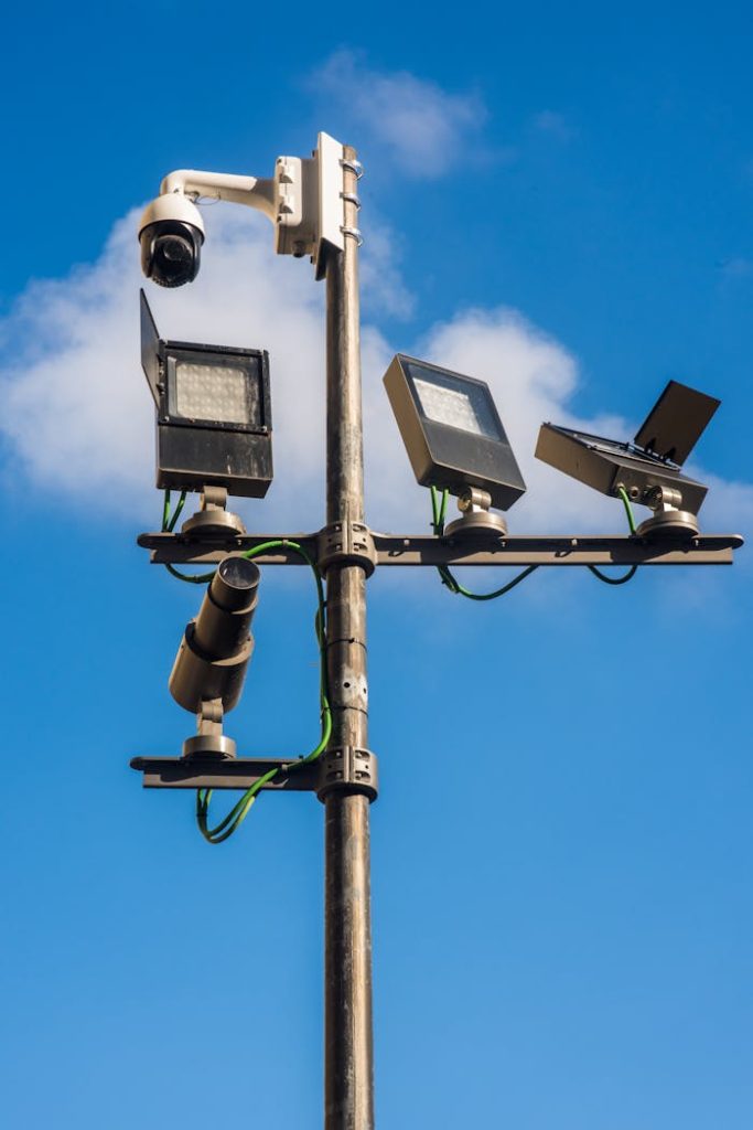 Close-up view of multiple surveillance cameras mounted on a pole against a clear blue sky.