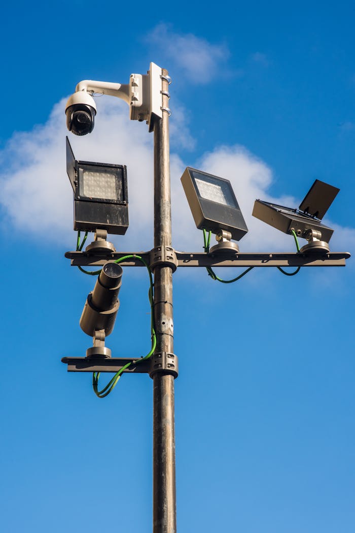 Close-up view of multiple surveillance cameras mounted on a pole against a clear blue sky.